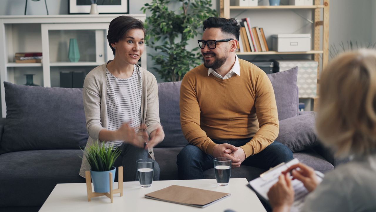 A couple discussing with a therapist during a counseling session indoors.