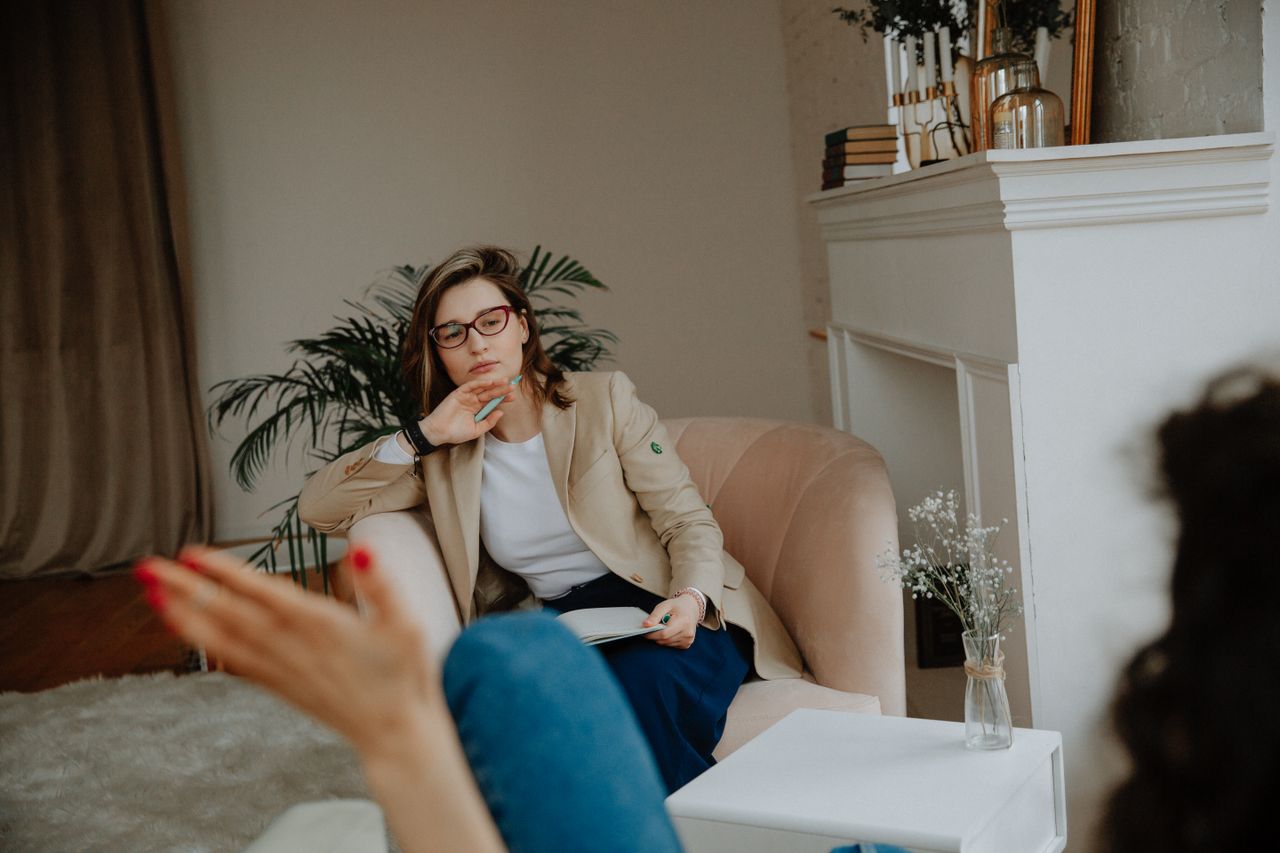 gallery-01 A woman counselor attentively listens during a therapy session in a cozy office environment.