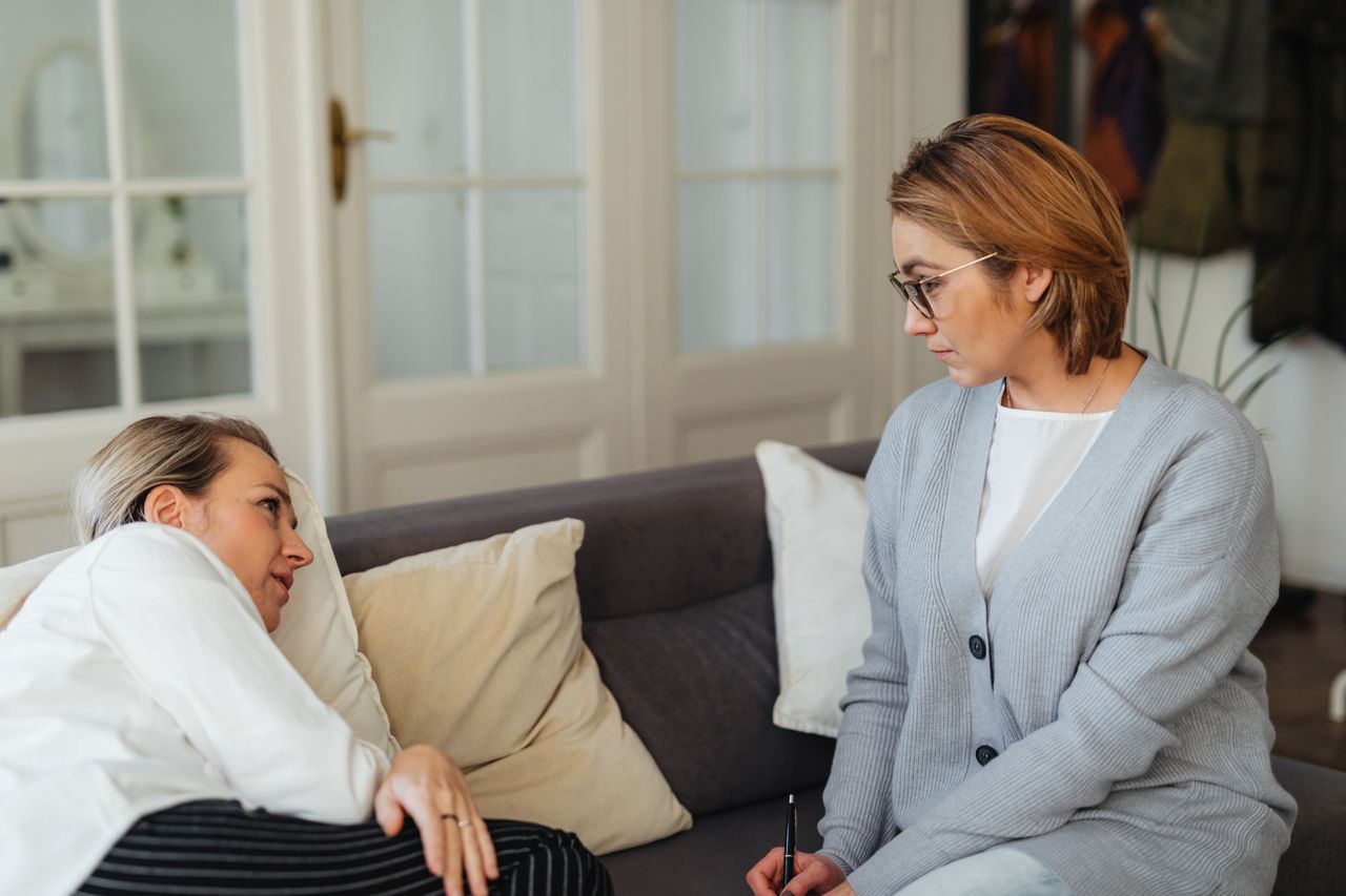 gallery-05 A therapist attentively listens to a client during a counseling session in a cozy indoor setting.