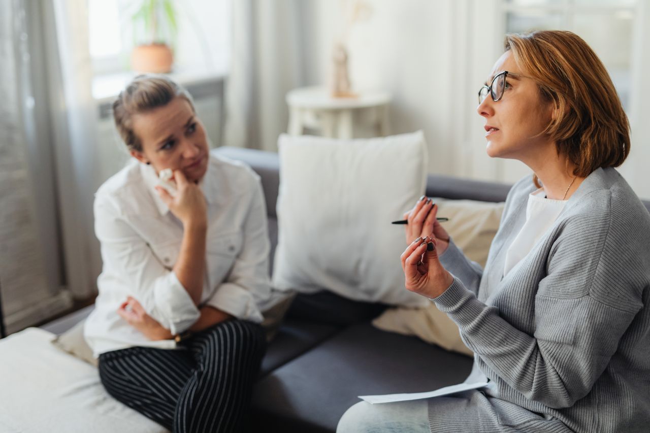 About Two women engaged in a thoughtful counseling session in a cozy indoor setting.