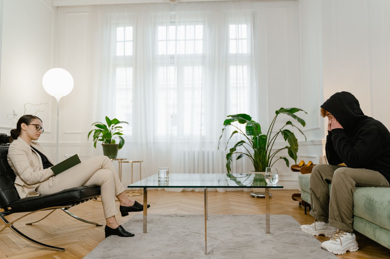 gallery-02 A therapist listens to a patient in a comfortable office setting. The atmosphere is calm and professional.
